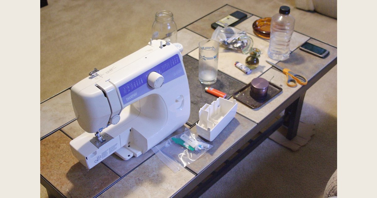 A vintage black sewing machine sits on a wooden worktable.