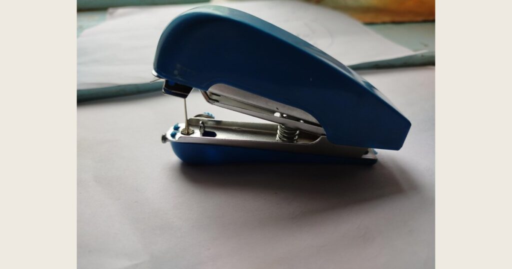Compact blue handheld sewing machine viewed from the side